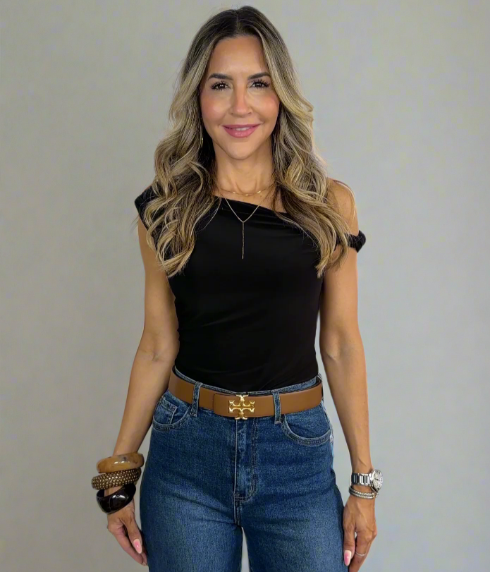 Woman wearing a black top and blue jeans with a white background