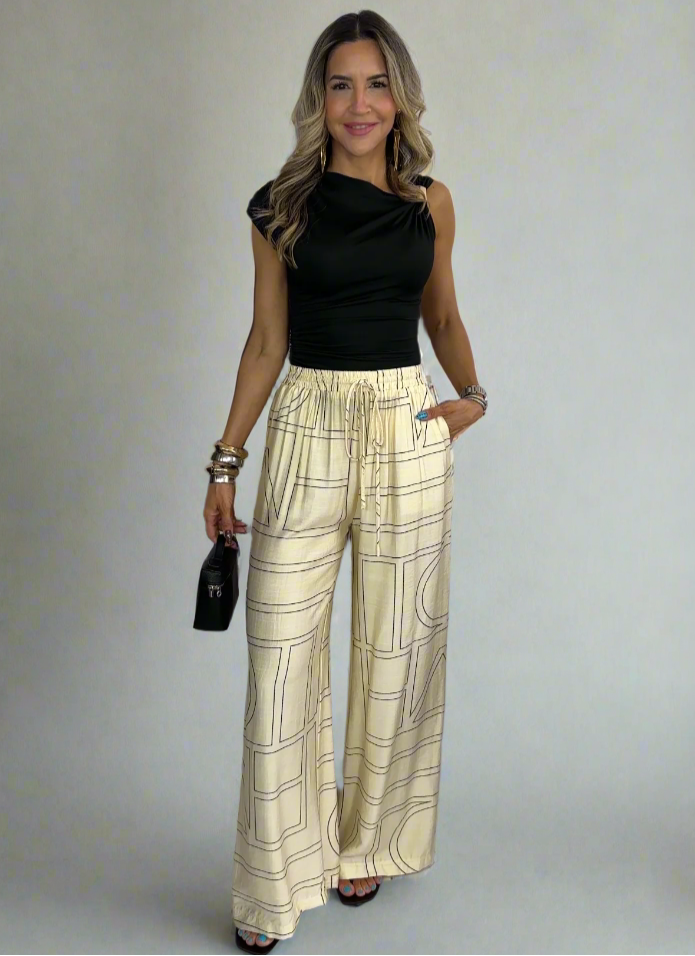 Woman wearing a black top and checkered pants against a white background