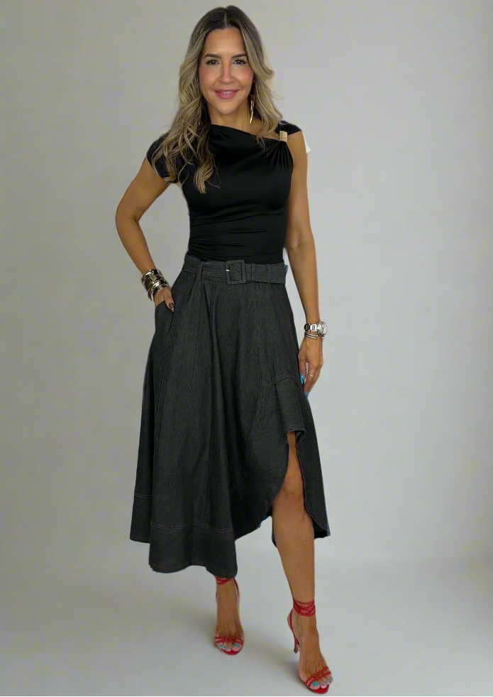 Woman wearing a black top and skirt standing against a white background