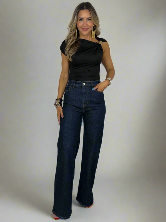 Woman wearing a black top and blue jeans against a white background