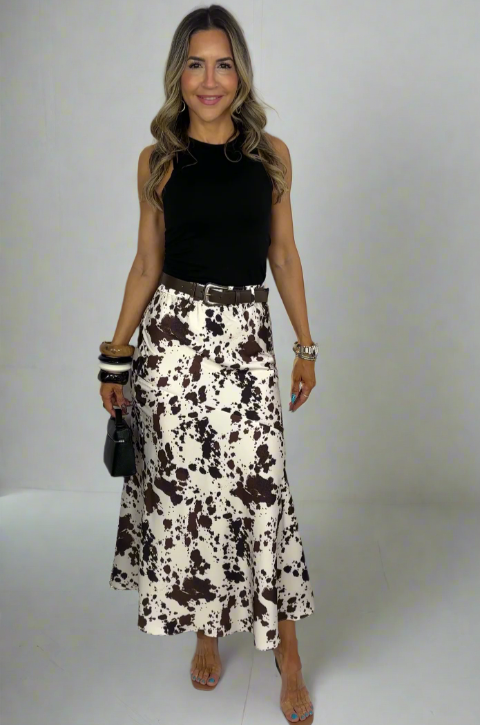 Woman wearing a black sleeveless top and patterned skirt on a white background