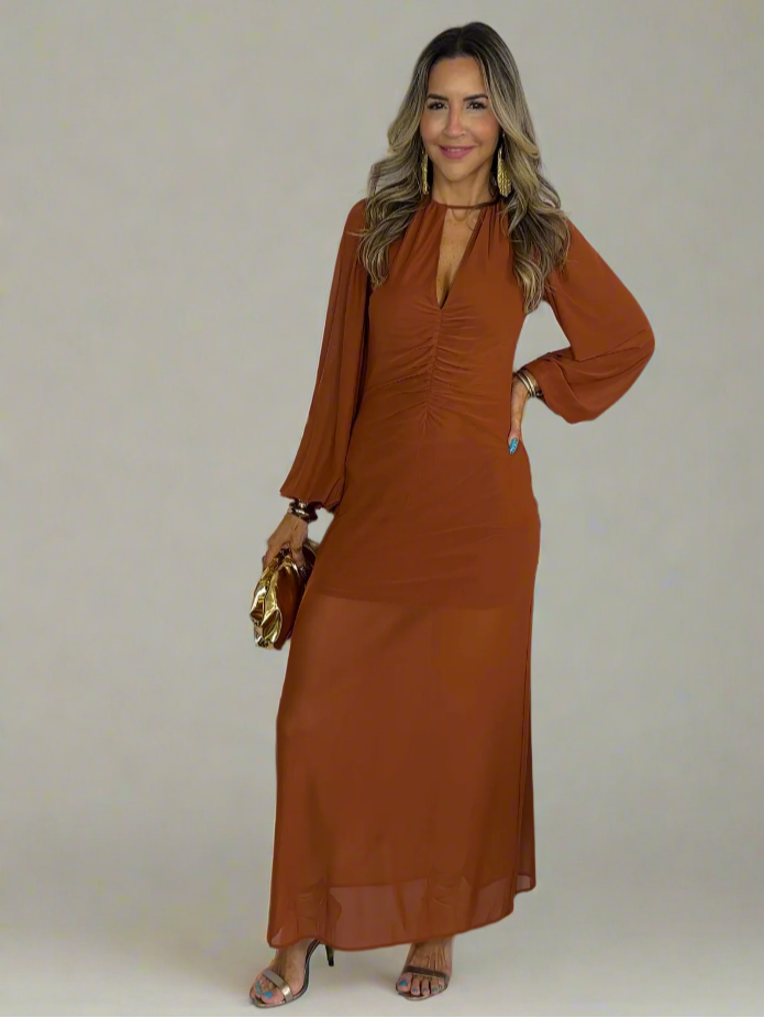 Woman wearing a long rust-colored dress against a white background