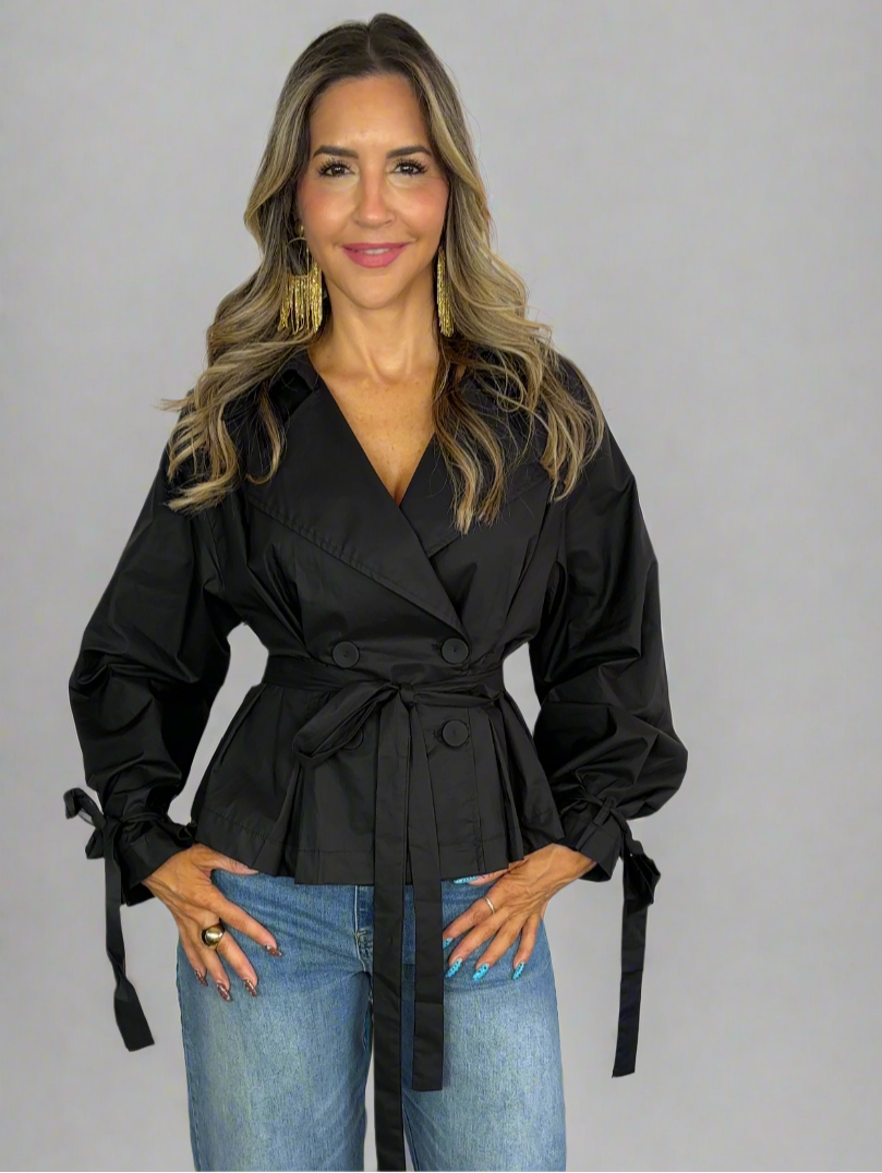 Woman wearing a black top and blue jeans on a plain background