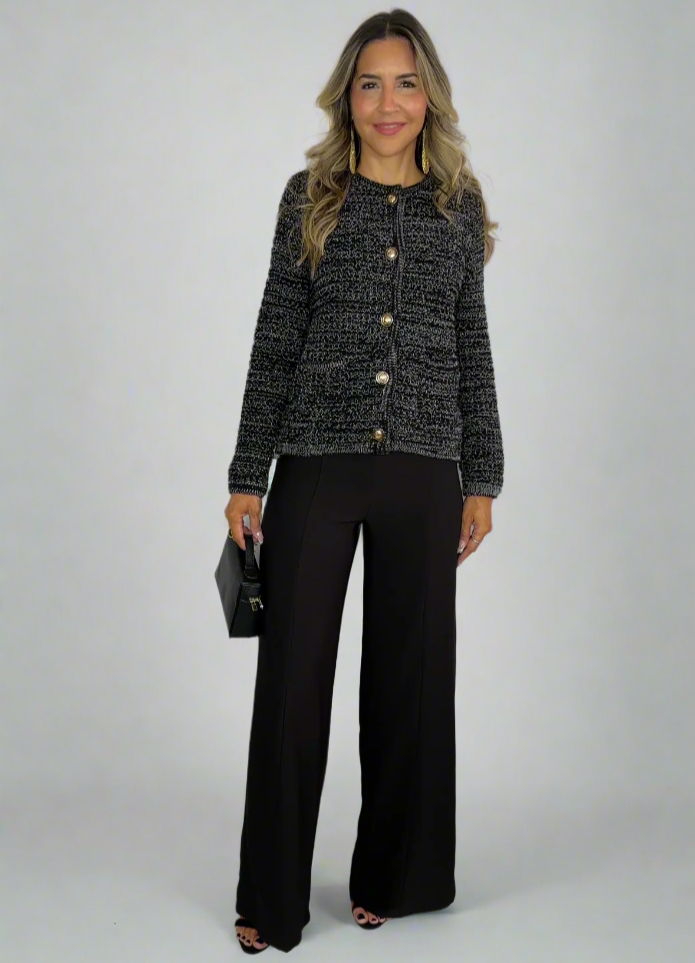 Woman wearing a patterned jacket and black pants against a white background