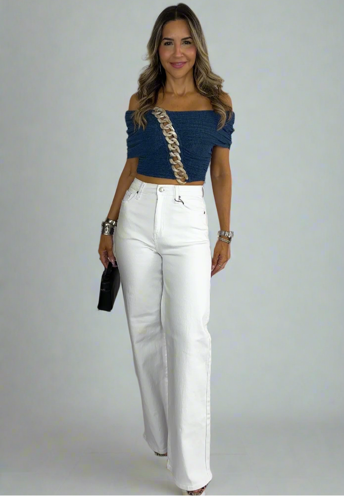 Woman wearing a blue top and white pants against a white background