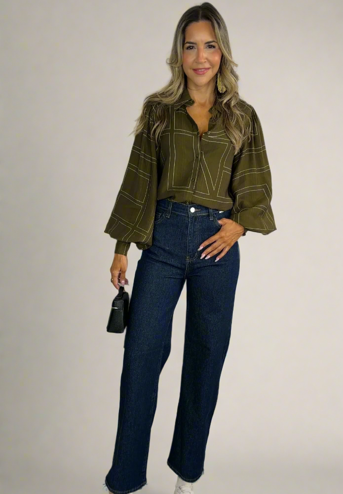 Woman wearing a green jacket and blue jeans against a white background