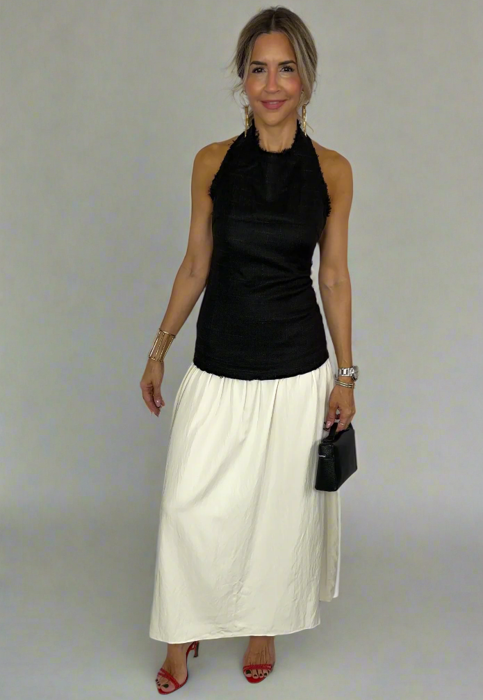 Woman wearing a black halter top and white skirt against a white background