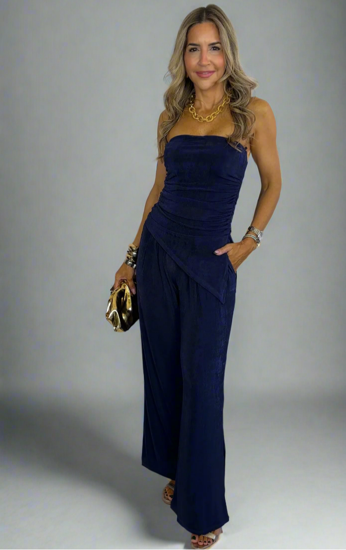 Woman wearing a strapless navy jumpsuit against a white background