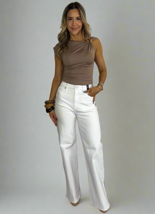 Woman wearing a brown sleeveless top and white pants on a white background