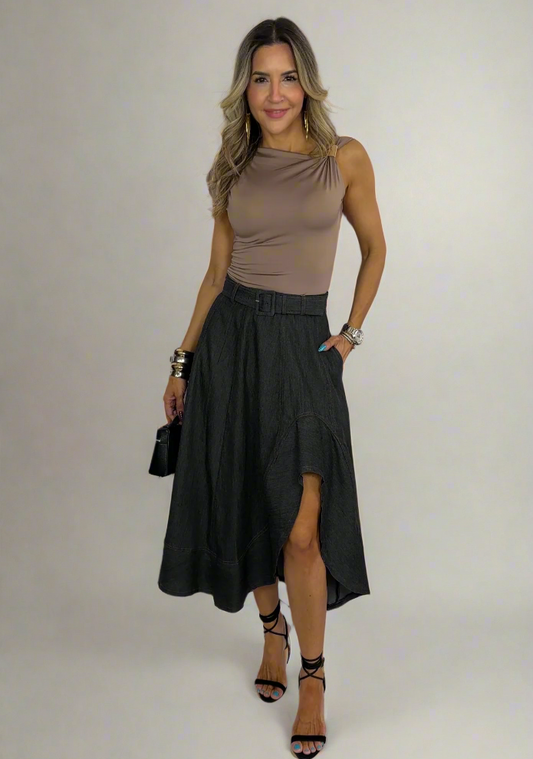 Woman wearing a brown sleeveless top and black skirt with a white background
