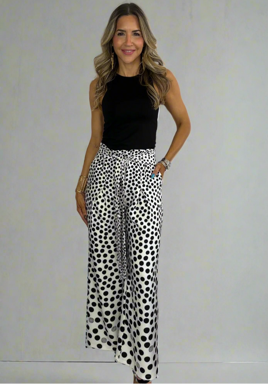 Woman wearing a black top and white polka dot pants on a white background