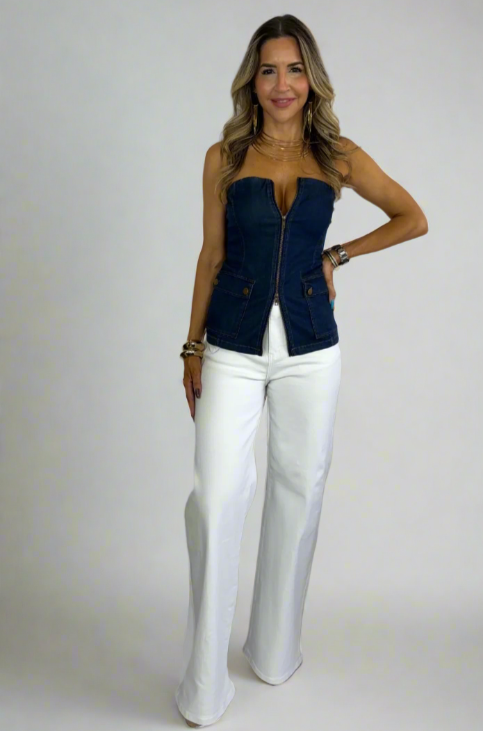 Woman wearing a navy blue top and white pants on a white background