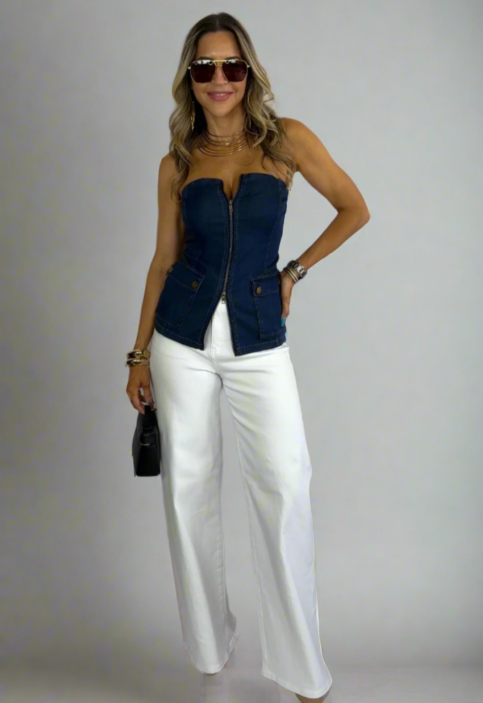 Woman wearing a blue top and white pants against a white background