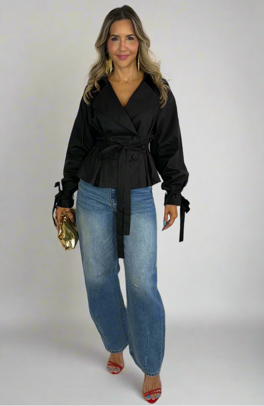 Woman wearing a black top and blue jeans on a white background
