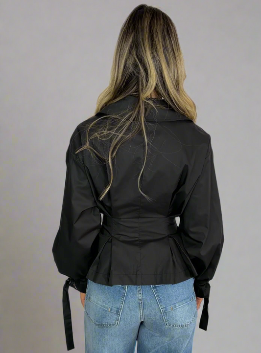 Person wearing a black jacket and blue jeans on a white background