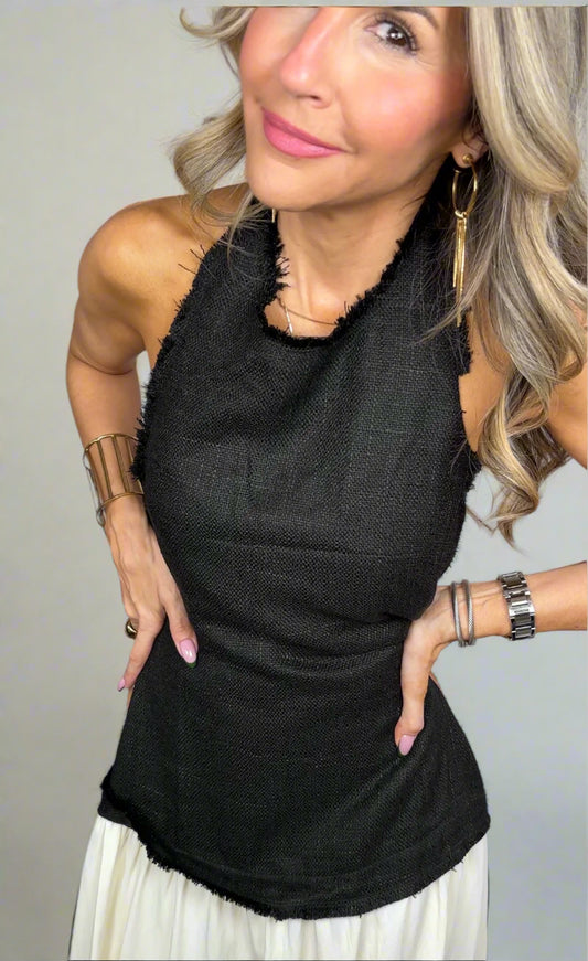 Woman wearing a black sleeveless top with a textured design against a neutral background